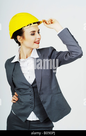 Imprenditrice che indossa un casco giallo sorridente Foto Stock