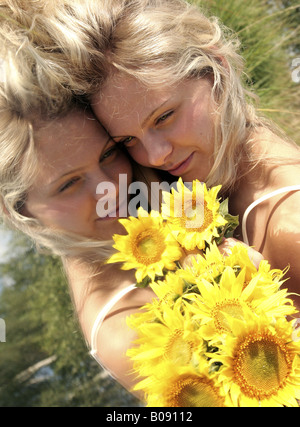 Ritratto di giovani biondo donne, giacenti su uno specchio con girasoli in giardino Foto Stock