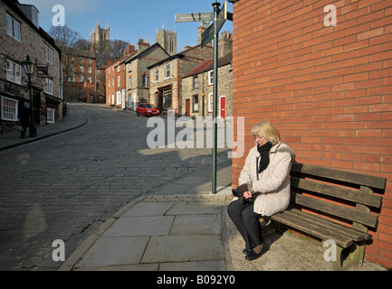 Donna di mezza età in appoggio sulla panca in legno Lincoln City Lincolnshire Inghilterra Foto Stock