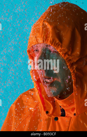 Uomo che indossa un arancione impermeabile, slicker sotto la pioggia Foto Stock