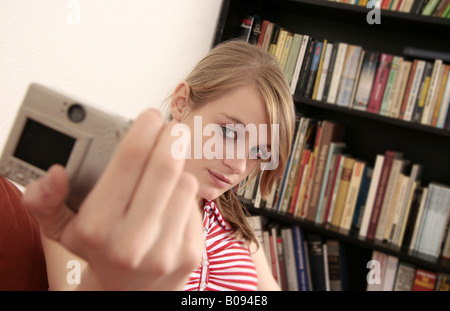 Giovane donna di fronte a libri prende una foto di sé Foto Stock