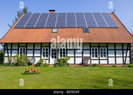 Tradizionale semi-struttura di legno casa con pannelli solari montati sul tetto, Strohen, Bassa Sassonia, Germania. Foto Stock