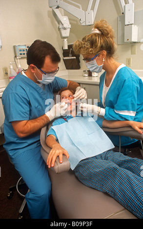 Un dentista e assistente di lavoro su un preoccupato per il bambino Foto Stock