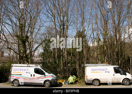 Due BT openreach furgoni con gli ingegneri di telefono tra inginocchiato sul terreno lavorando su linee telefoniche Foto Stock