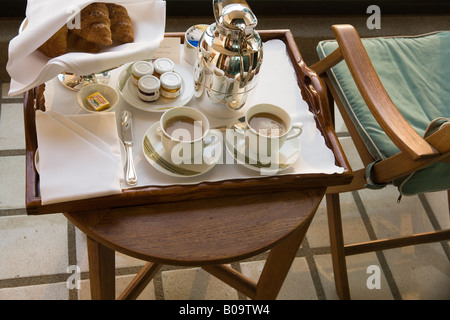 Tavolo per la colazione in un hotel con croissant e caffè due tazze riempite con nero caffè al mattino presto Foto Stock