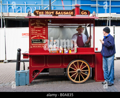 Il cliente ha appena acquistato uno snack, un hot dog, dal titolare di stallo rimane per avere una conversazione testuale. Fitzroy Street. Foto Stock