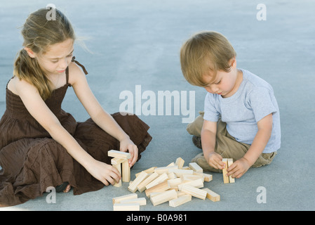 Fratello e Sorella di seduta sul terreno, giocando con la costruzione di blocchi insieme Foto Stock