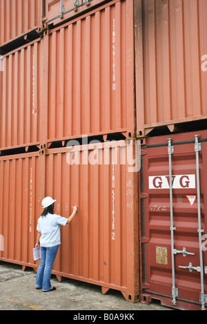 Donna in hard hat iscritto sul metallo unità di storage, vista posteriore Foto Stock