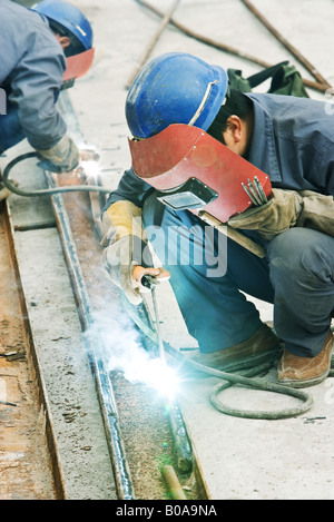 Lavoratore utilizzando la torcia di saldatura in cantiere, vista laterale Foto Stock