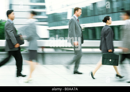 Maschio e femmina professionisti camminando sul marciapiede, movimento sfocato Foto Stock