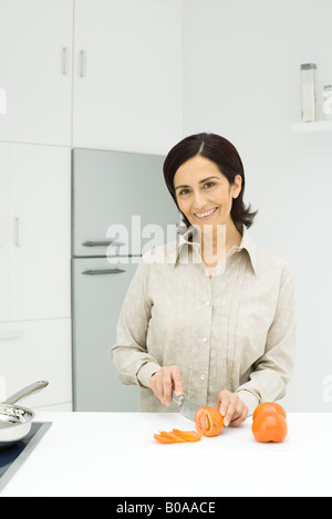 La donna per affettare i pomodori in cucina Foto Stock