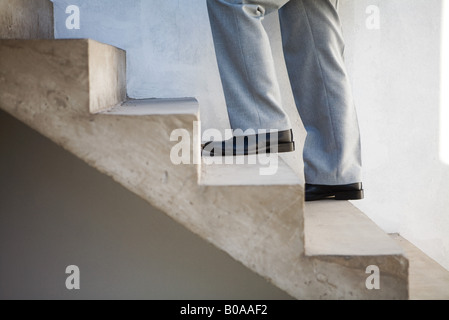 Uomo che cammina su scala, vista laterale, ritagliato Foto Stock