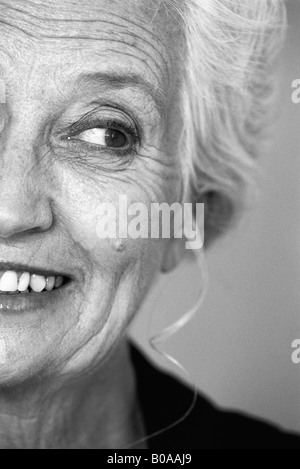 Senior donna che guarda lontano e sorridente, ritratto, ritagliato Foto Stock