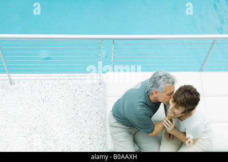 Giovane seduti sul balcone, uomo donna baciando la guancia, ad alto angolo di visione Foto Stock