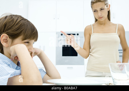 Ragazzo busbana francese al tavolo da cucina, madre scuotendo il suo dito Foto Stock