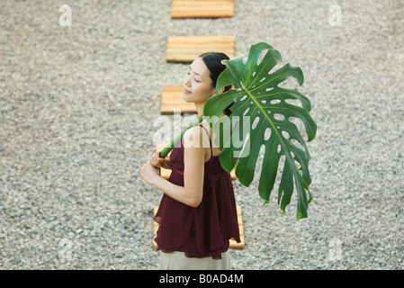 Donna sul sentiero holding di foglie di palma a occhi chiusi ad alto angolo di visione Foto Stock