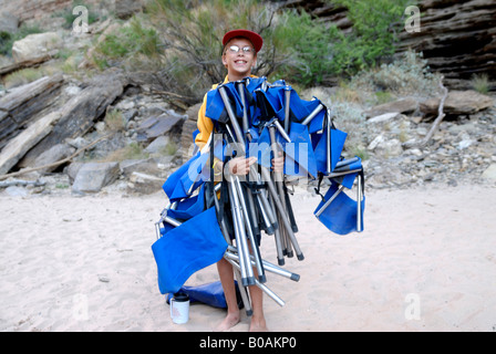 Ragazzo caricato con sedie da campeggio su un banco di sabbia in background il Fiume Colorado nel Grand Canyon Arizona USA MR Foto Stock