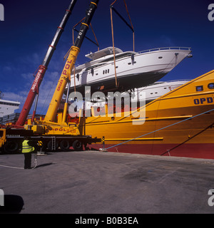 Johnson 77 luxury motor yacht superyacht nel corso di sollevare il contenitore dalla nave nel porto di Palma de Mallorca Foto Stock