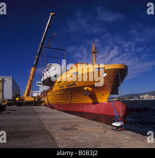 Johnson 77 luxury motor yacht superyacht nel corso di sollevare il contenitore dalla nave nel porto di Palma de Mallorca Foto Stock