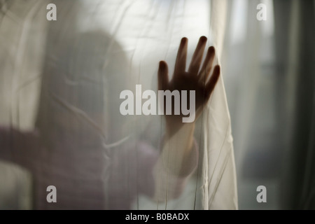 Ragazza di età compresa tra i 4 anni sta dietro tendina Foto Stock