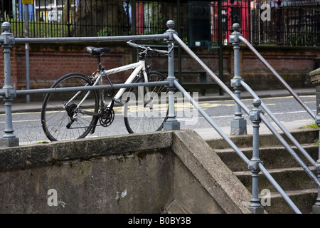 Bike appoggiato e bloccato contro la ringhiera Foto Stock