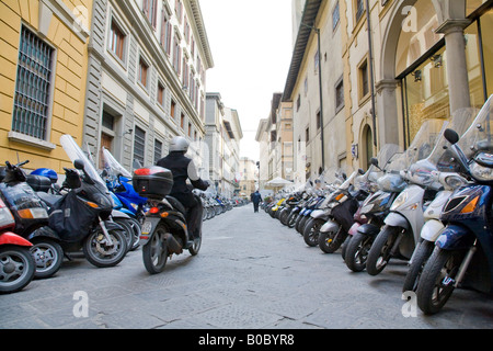 Un motore ciclista nel centro di Firenze su una strada piena di parcheggiata cicli del motore Foto Stock