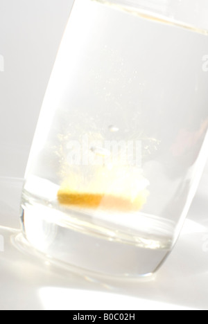 Arancione effervescente vitamina tablet è scesa in un bicchiere di acqua Foto Stock