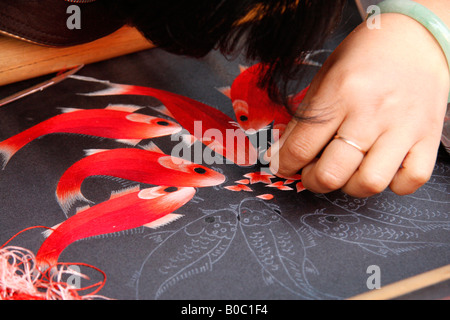 Mani esperte facendo un sottilissimo filo di seta design di ricamo di pesce . Foto Stock
