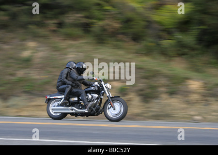 Motociclista con pillion passeggero viaggia verso il basso una strada di campagna. Foto Stock