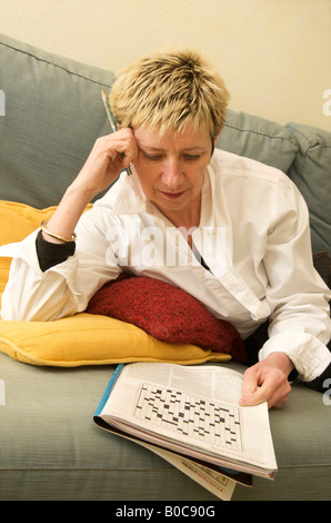 Donna di mezza età facendo un cruciverba Foto Stock