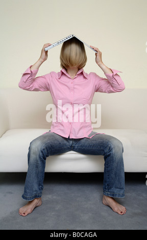 Donna con notebook sul suo capo Foto Stock