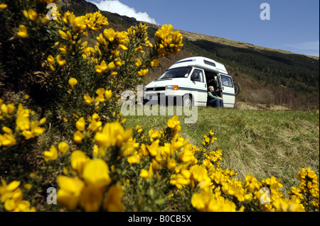 Una donna gode di clima soleggiato e la libertà di un camper vacanza nelle Highlands della Scozia.UK. Foto Stock