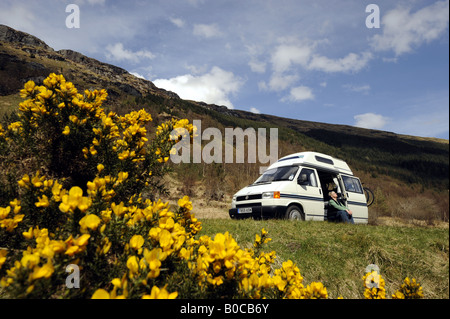 Una donna gode di clima soleggiato e la libertà di un camper vacanza nelle Highlands della Scozia.UK. Foto Stock