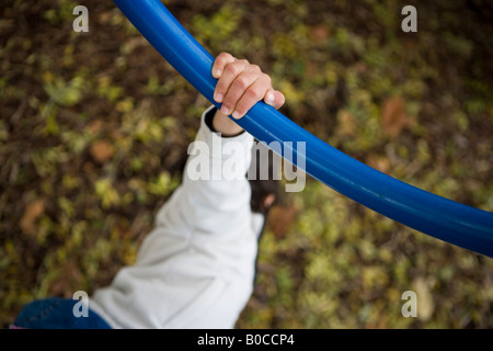 Parco avventura a scuola locale di Palmerston North Nuova Zelanda. Ragazza afferra la barra blu del telaio di arrampicata Foto Stock