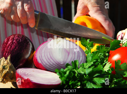 Le mani di una donna anziana il taglio di verdure fresche Foto Stock