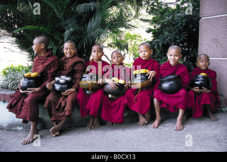 Fila di novizi buddisti monaci con offertorio bocce in Yangon Myanmar Foto Stock