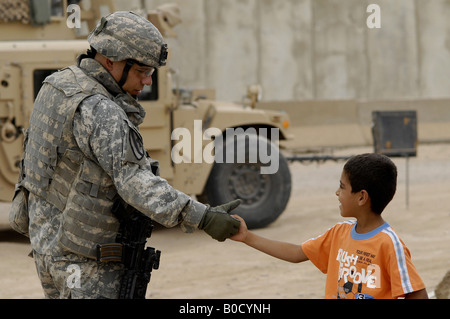 U S Army Maj Robert Rodriguez scuote le mani locale con un bambino durante una visita al mercato Taji in Iraq Foto Stock