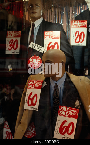 Mannequins indossando bargain office abiti e cappotti riempire un signor Byrite mens' a buon mercato negozio di abbigliamento finestra durante una vendita a Londra Foto Stock