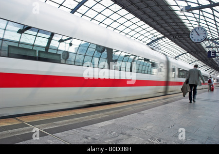 I passeggeri con la valigia a piedi come sfocata ghiaccio intercity express treno tira in Berlin Spandau stazione ferroviaria Foto Stock