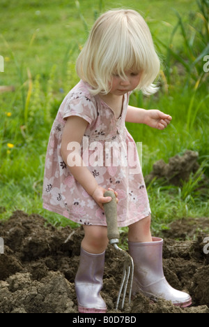 Stock Foto di un po' di capelli biondi due anno vecchia ragazza aiutando con il giardinaggio Foto Stock