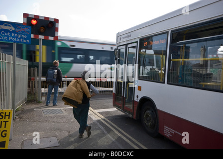 Il bus di pedoni in attesa passaggio a livello Foto Stock