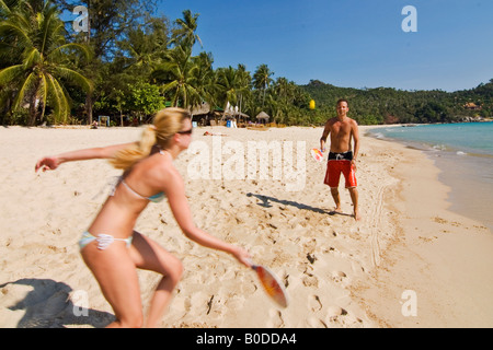 Un giovane gode di un divertente gioco di paddle ball a una spiaggia tropicale in Tailandia Foto Stock