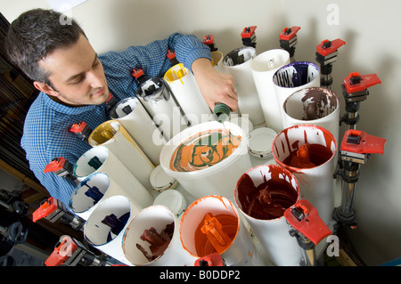 Un uomo per il mescolamento di vernici e colori di miscelazione in un workshop realizzazione su misura di vernice naturale per l'ordine. Foto Stock