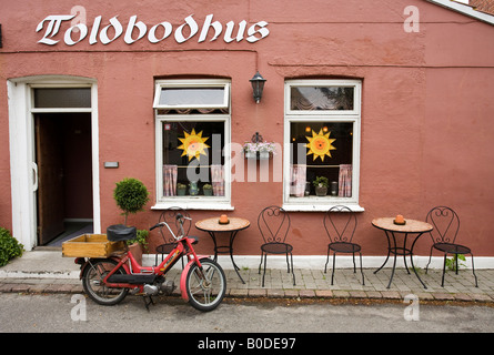 Cafe consegna. Un piccolo cafe Toldbodhus con un motore di consegna Consegna assistita bicicletta tirata in alto nella parte anteriore di esso Foto Stock