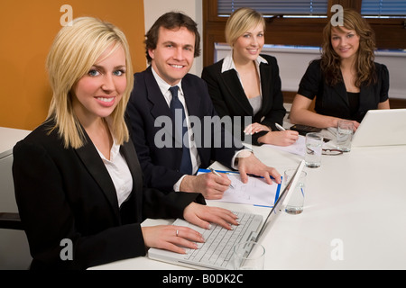 Tre dirigenti femmine ed un maschio avente una riunione in una sala riunioni il focus è sul biondo imprenditrice in primo piano Foto Stock