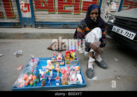 Venditore ambulante seduto sulla strada vendendo i suoi giocattoli Foto Stock