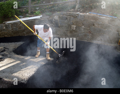 Giorno operaio spargimento su asfalto appena costruito passo carraio Foto Stock