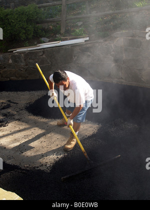 Giorno operaio spargimento su asfalto appena costruito passo carraio Foto Stock