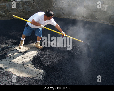 Giorno operaio spargimento su asfalto appena costruito passo carraio Foto Stock