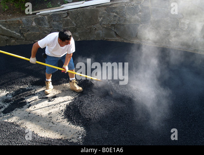 Giorno operaio spargimento su asfalto appena costruito passo carraio Foto Stock